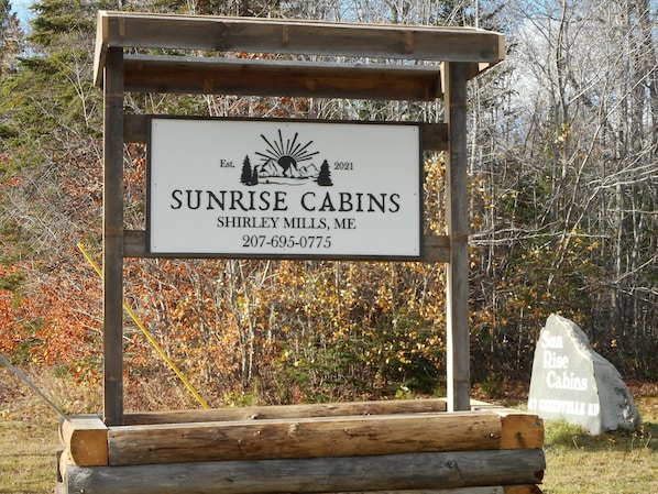 A wooden signboard for Sunrise Cabins with contact information and establishment year.