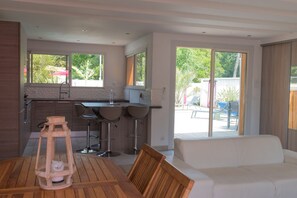 A modern kitchen with a dining area, a white sofa, and a view of the outdoors. - Superbe Villa Avec Piscine, spa et Boulodrome sur Cassy, à 3 mn D'andernos (Lanton)