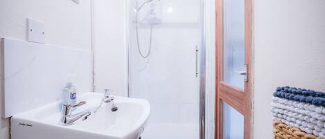 A bathroom with a white sink, mirror, and shower.
