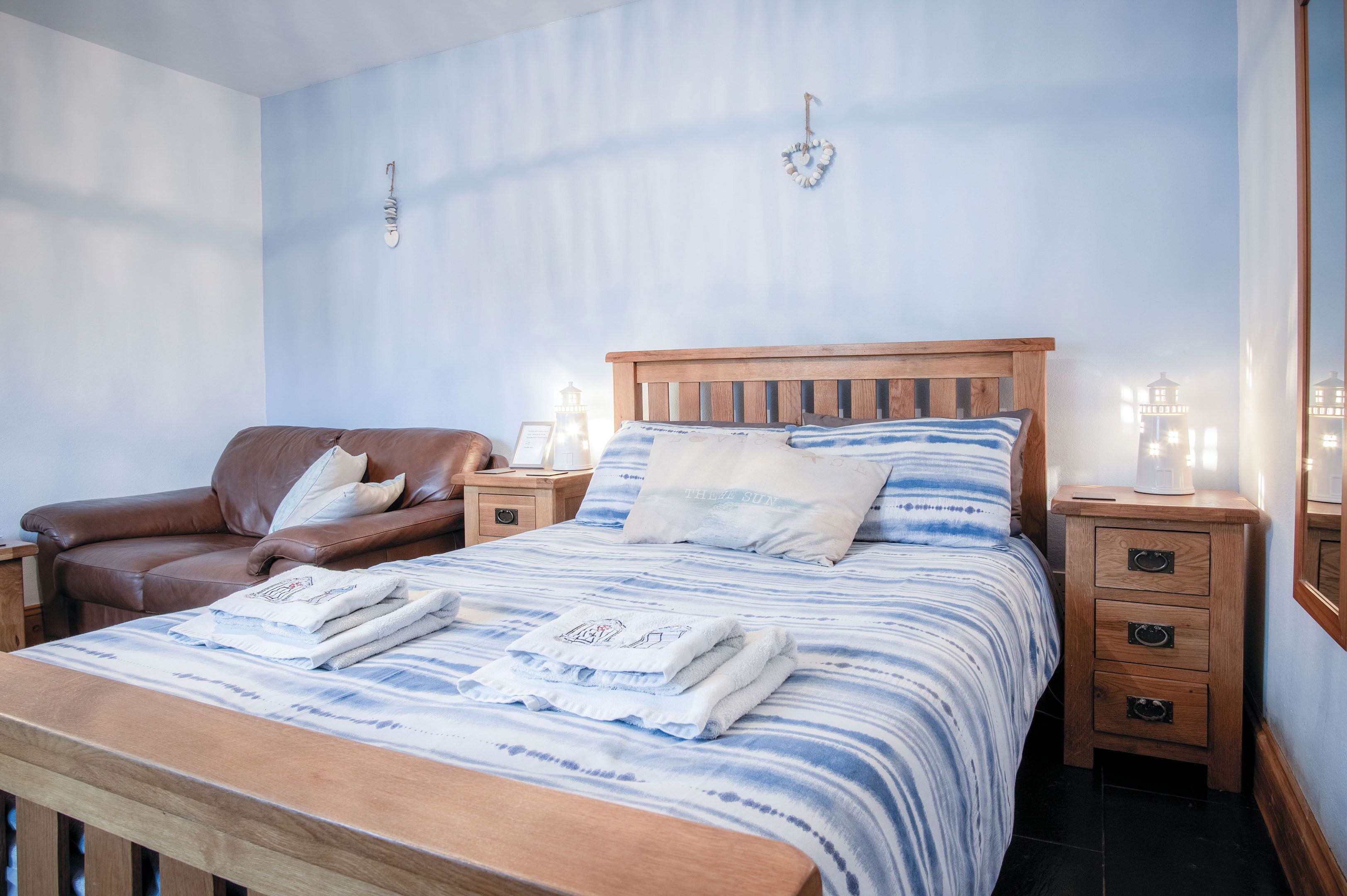 A bedroom with a wooden bed, a leather chair, bedside tables with lamps, and a nightstand.