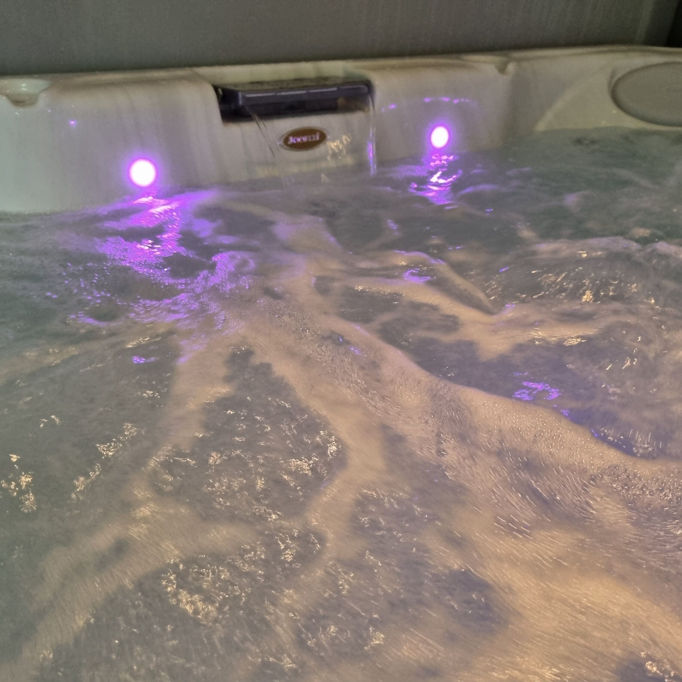 Un jacuzzi con burbujas visibles y un panel de control con el logotipo de la marca.