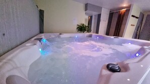 Ein Whirlpool mit blauen LED-Leuchten, eine Topfpflanze und eine Steinwand.