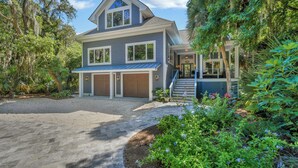 A two-story house with a covered porch, a garage, and a staircase leading to the second floor. - 6 Laurel - Luxury kitchen, pool, spa, and fire pit. 2 minute walk to beach. Sleeps 23. (Hilton Head Island)