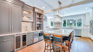 A modern kitchen with a large island, stainless steel appliances, and a view of the outdoors. - 6 Laurel - Luxury kitchen, pool, spa, and fire pit. 2 minute walk to beach. Sleeps 23. (Hilton Head Island)