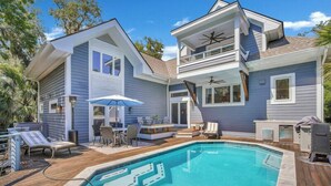 A two-story house with a swimming pool, outdoor furniture, and a covered patio area. - 6 Laurel - Luxury kitchen, pool, spa, and fire pit. 2 minute walk to beach. Sleeps 23. (Hilton Head Island)