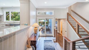 A modern kitchen with a large island, a dining area with outdoor seating, and a staircase leading to a second floor. - 6 Laurel - Luxury kitchen, pool, spa, and fire pit. 2 minute walk to beach. Sleeps 23. (Hilton Head Island)