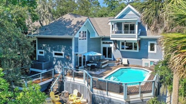 A two-story house with a swimming pool, outdoor seating, and a staircase leading to a deck. - 6 Laurel - Luxury kitchen, pool, spa, and fire pit. 2 minute walk to beach. Sleeps 23. (Hilton Head Island)
