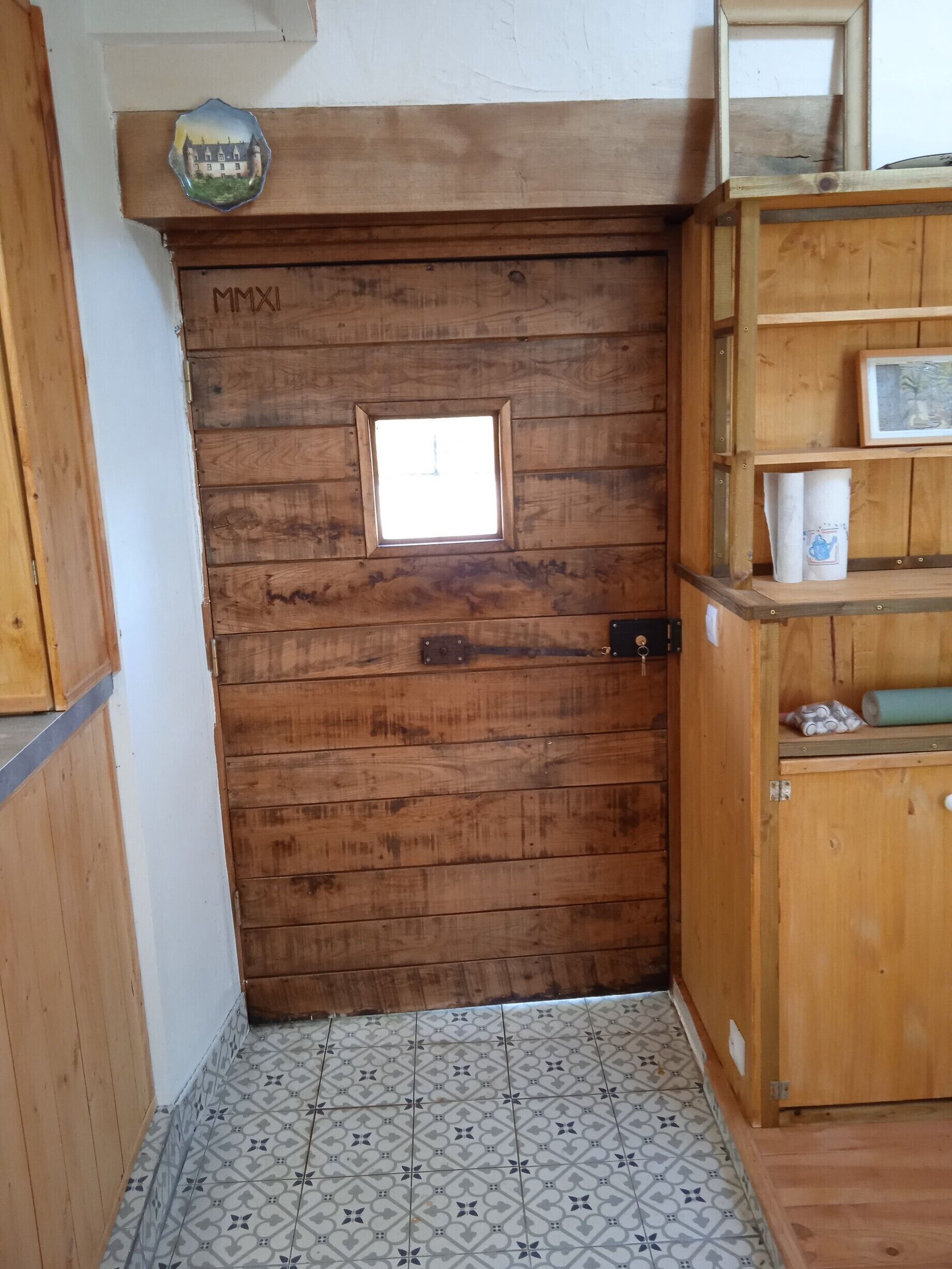 Une porte en bois avec une petite fenêtre et une poignée en métal.