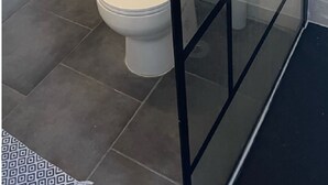 A bathroom with a toilet, a glass partition, and tiled walls. - Maison de 50m2 Avec Piscine Commune (Fréjus)