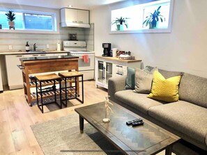 Cozy living space with a kitchenette, sofa, coffee table, and wooden bench.