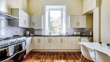 A modern kitchen with white cabinets, a stove, and a window.