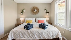 A neatly made bed with a white quilt, two rolled towels, and two bedside lamps. - TOP-RATED! HOT TUB, KAYAKS, FISHING, BOAT DOCK! Granbury Paddle and Play Escape! (Granbury)