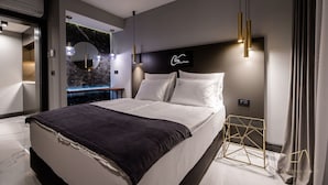 Una camera da letto moderna con un letto grande, una parete in marmo e un comodino geometrico dorato.