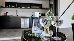 Una cucina moderna con un piano di lavoro nero, una bottiglia di gin e due bicchieri con la cannuccia.