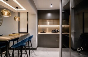 Eine moderne Küche mit dunkler Arbeitsplatte, Edelstahlgeräten und einer Bar mit Hockern.