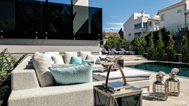 Un'area salotto esterna moderna con piscina, poltrone relax e un design contemporaneo.