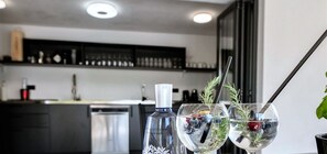 Eine moderne Küche mit schwarzem Arbeitsplatz, einer Gin-Flasche und zwei Gläsern mit Trinkhalm.