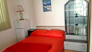 Un dormitorio con cama, mesita de noche, cómoda y ventana.