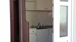 Un pasillo estrecho que conduce a una cocina con armarios blancos, una encimera y un salpicadero de azulejos.