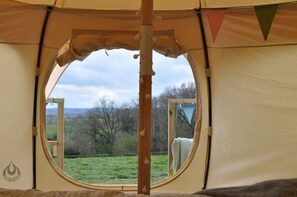 A circular window in a tent with a view of a grassy field and trees. - Lovely Spacious Lotus Bell Tent in Shaftesbury, UK (Shaftesbury)