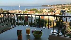 Un balcón con una mesa, un vaso de jugo, un tazón y un tarro de nueces.