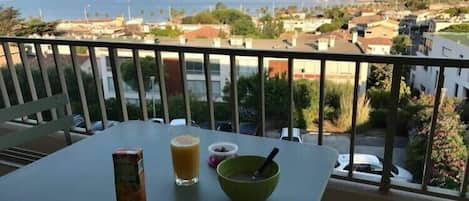 A balcony with a table, a glass of juice, a bowl, and a jar of nuts.