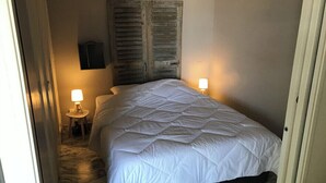 Un dormitorio con una cama, dos lámparas de noche, un cabecero de madera y una mesita.