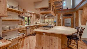 Une cuisine spacieuse dotée de meubles en bois, d’un îlot central et d’un coin bar avec des tabourets.