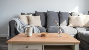 A modern living room with a grey sofa, a wooden coffee table, and a white side table. - Modern 1BED Central Birmingham Apartment- Sleeps 4 (Birmingham)