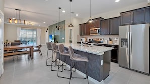 Una cocina moderna con una isla central, electrodomésticos de acero inoxidable y una zona de comedor con taburetes de bar.
