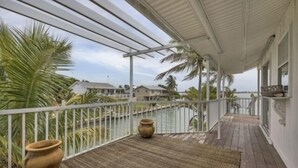 A covered balcony with a view of the water, palm trees, and a rustic pot. - Boaters Paradise  ***Palm Point*** Little Gasparilla North Canal on the POINT (Placida)