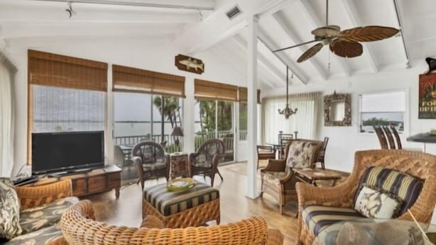 A spacious living area with wicker furniture, a flat-screen TV, and large windows offering views of the outdoors. - Boaters Paradise  ***Palm Point*** Little Gasparilla North Canal on the POINT (Placida)