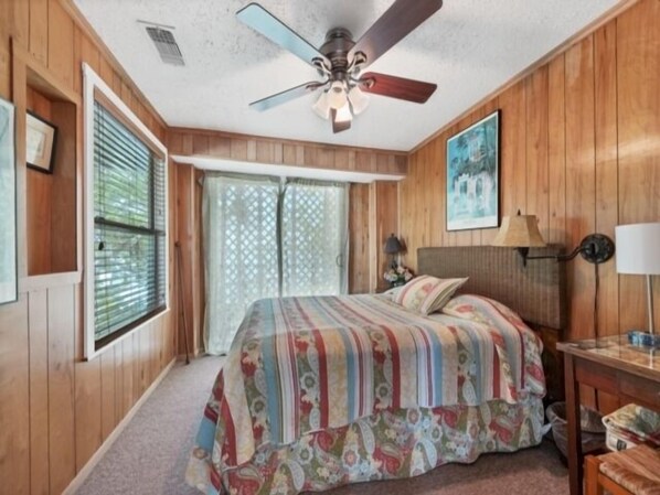 A bedroom with a bed, a ceiling fan, a window with blinds, a door with a glass panel, and a painting on the wall. - Boaters Paradise ***Palm Point*** Little Gasparilla North Canal on the POINT (Placida)