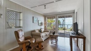 A living room with a wooden floor, a leather chair, a sofa, a small table, and a TV on a stand. - Boaters Paradise  ***Palm Point*** Little Gasparilla North Canal on the POINT (Placida)
