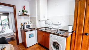 A compact kitchen with a washing machine, microwave, and sink. - Marbella Village | Studio with balcony (Marbella)