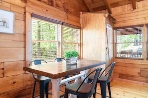 Cozy cabin interior with a dining area, wooden table, and comfortable seating for four.