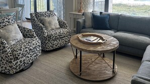 A living room with a view of the ocean, featuring a sofa, two leopard print armchairs, a round coffee table, and a ceiling fan. - 3 Bed~3 Bath~Sleeps 8~Duneridge Condo~Wrightsville Beach, NC (Wrightsville Beach)