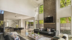 Un salon moderne avec un canapé noir, une table basse et un téléviseur fixé au mur.