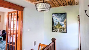 A staircase with wooden railings leading to a room with a wooden ceiling and a hanging light fixture.