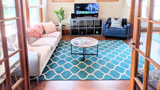 A living room with a sofa, a coffee table, a TV, and a patterned rug.
