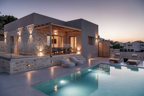 Ett modernt hus med en swimmingpool, stenmurar och en uteplats.