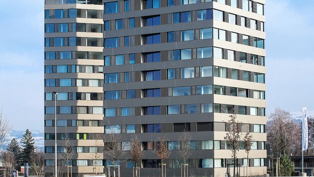 A modern high-rise building with multiple floors, large windows, and a flat roof.