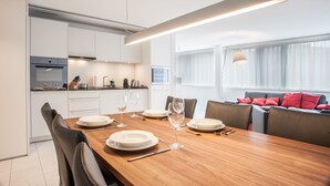 A modern dining area with a wooden table set for four, white plates, and wine glasses.