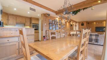 Une table à manger en bois, des chaises, un lustre et des tableaux encadrés accrochés au mur.