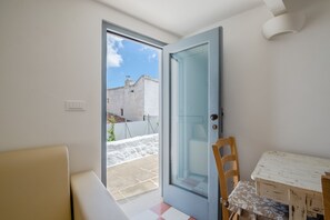 A room with a blue door, a small table with a patterned tablecloth, and a beige sofa. - Corso Italia Deluxe Apartment by Wonderful Italy (Ostuni)