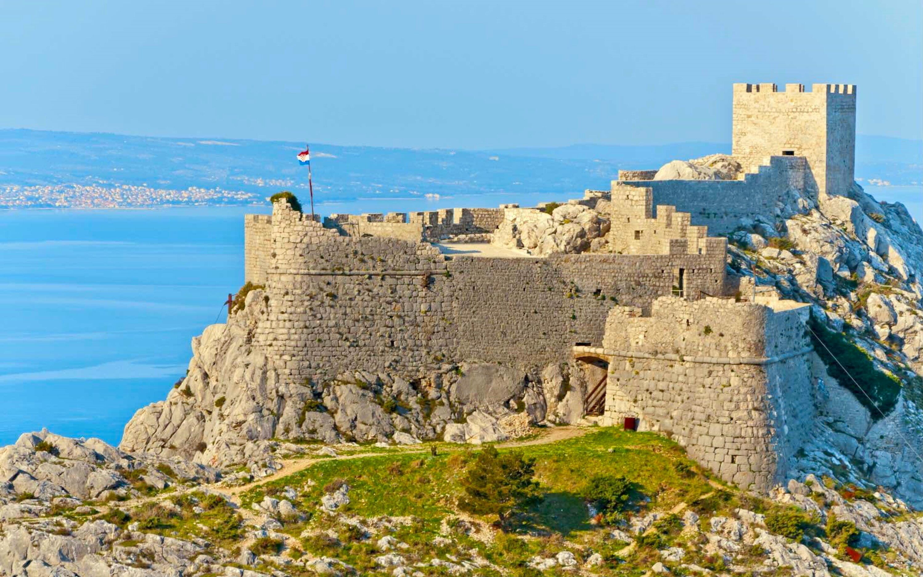 A historic stone fortress with a flag on top, overlooking a coastal area. - A3 - apt w. Patio, 3 min Walking From the Beach (Dugi Rat)