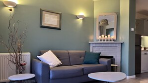 A modern living room with a grey sofa, a small round table, and a fireplace. - Bélicine, seafront apartment for 5 people  (LE CROTOY)