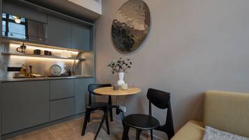 Una cocina moderna con armarios grises, una mesa redonda con dos sillas y un adorno en la pared.
