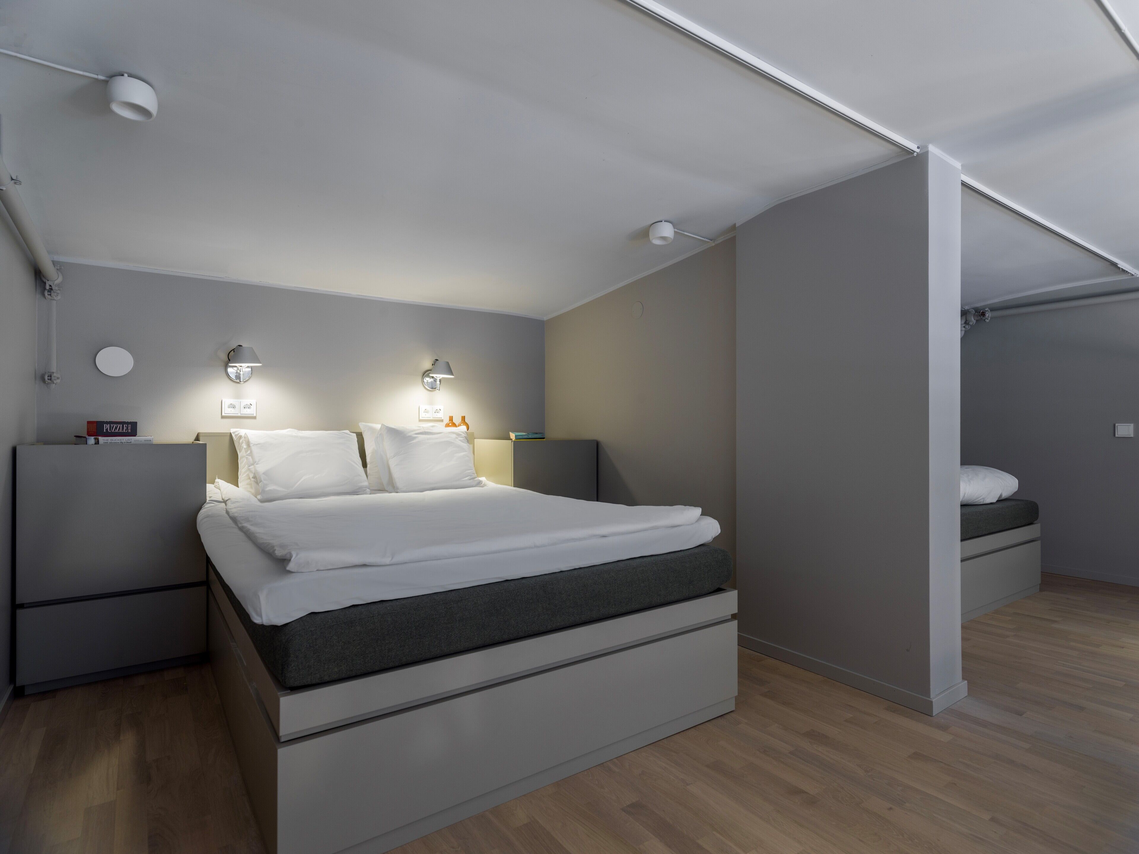 Une chambre à coucher moderne, avec un lit, des tables de chevet et des lampes fixées au mur.