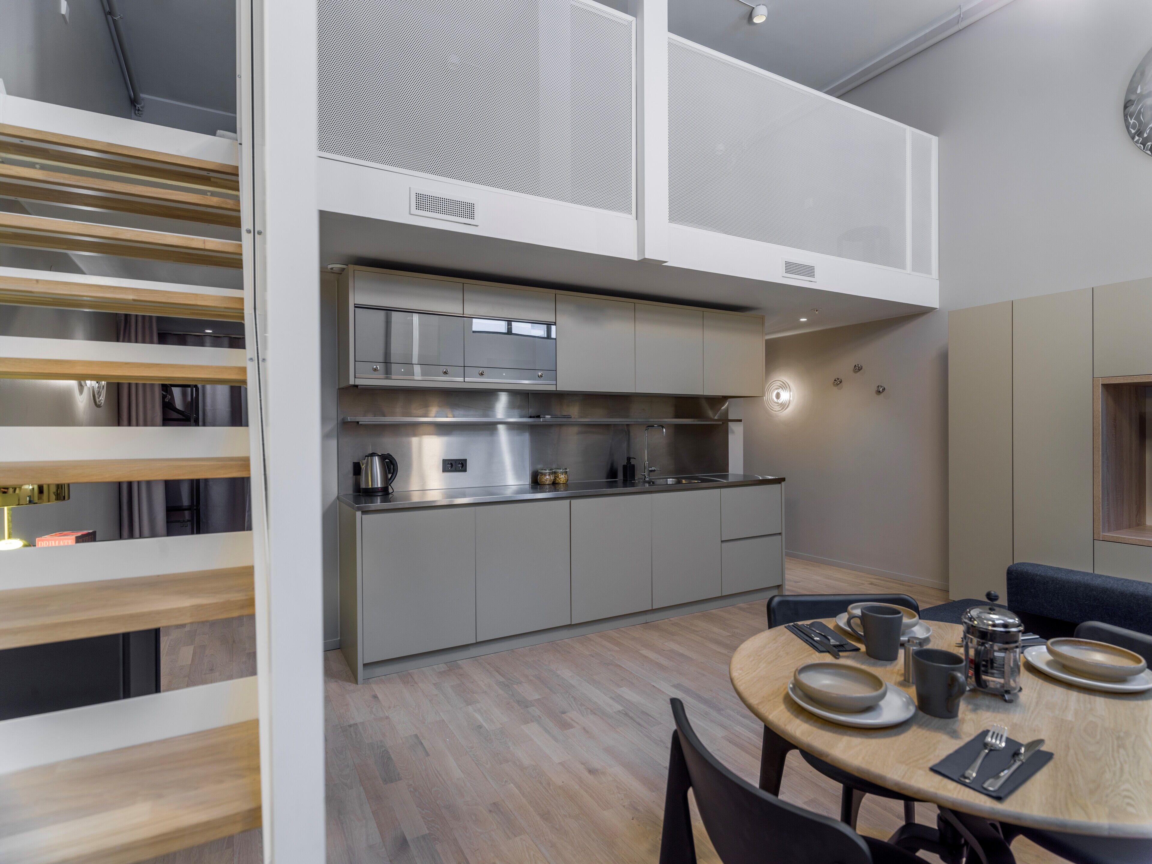 Una cocina moderna con electrodomésticos de acero inoxidable, un comedor con una mesa redonda y un banco empotrado.